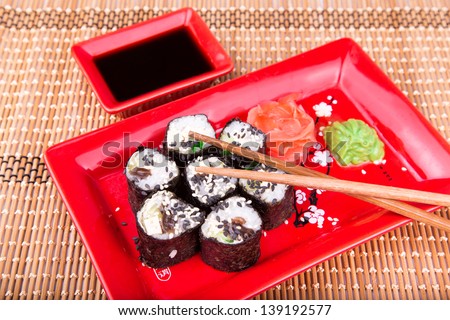 Vegetarian sushi roll served in a form of flower on a red plate on a bamboo mat