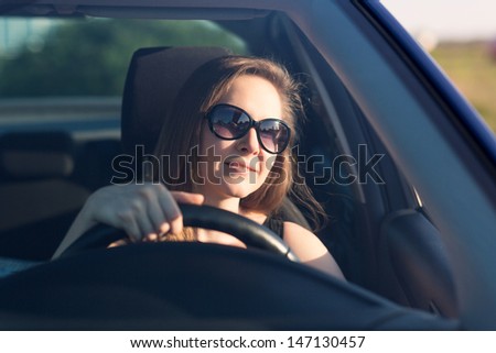 Beautiful businesswoman in sunglasses driving her car