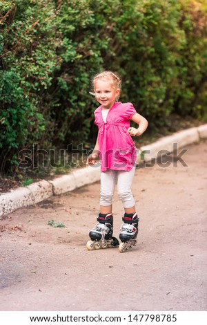 Little girl skating on roller skates at park, first attempt