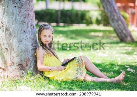 Cute little girl learning with tablet pc in the park
