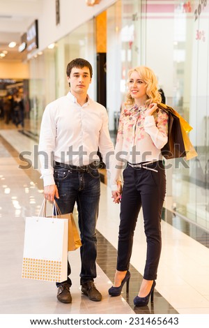 Happy young couple walking in the mall carrying shopping bags