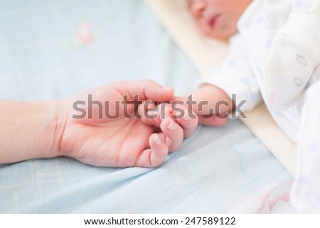 Mother holding the hand of her new born baby, shallow DOF