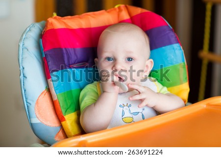Adorable baby eating in high chair. Baby\'s first solid food