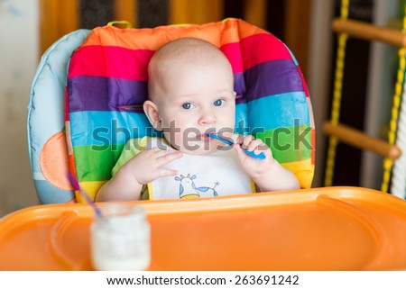 Adorable baby eating in high chair. Baby\'s first solid food