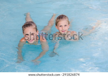 Two cute little girls in swimming pool posing