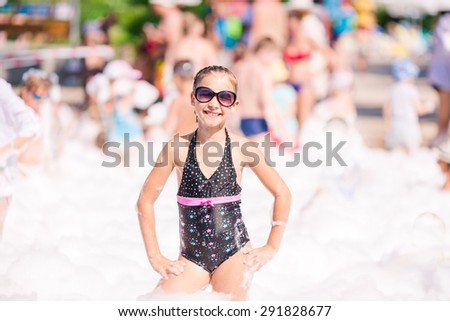 Foam Party on the beach. Cute little girl having fun and dancing.