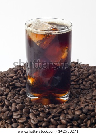 Iced coffee in glass on top of beans