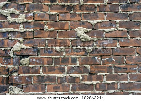 An old brick wall in English bond laid with alternating courses of headers and stretchers