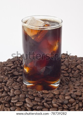 Iced coffee in a glass on pile of beans