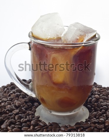 Iced coffee in a glass on pile of beans