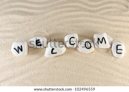 Welcome word on group of stones with sand as background