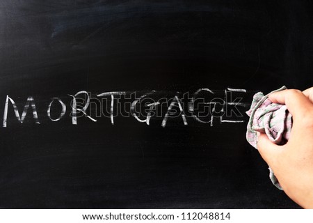 Hand wiping off mortgage on blackboard using rag