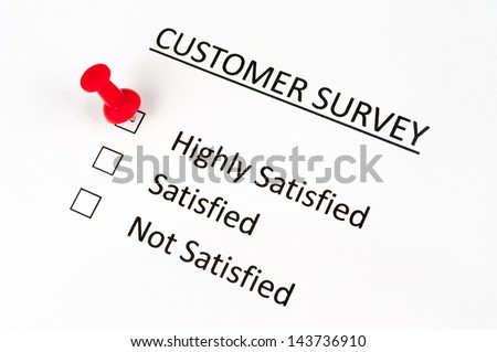 A thumbtack pinned on customer survey paper with options of highly satisfied, satisfied and not satisfied