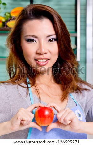 beutiful girl show apple sweet heart in kitchen (process skin tone)