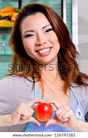 beutiful girl show apple sweet heart in kitchen (process skin tone)