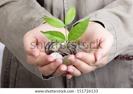 Businessman cover growing plant with coin money