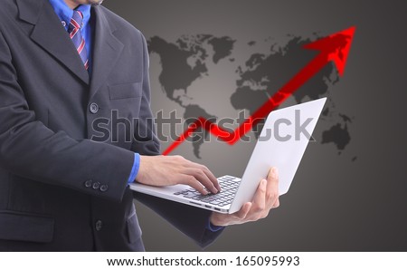 Businessman holding laptop for type something with growing graph