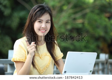 Young girl using laptop for search and send e mail to her friend in garden.