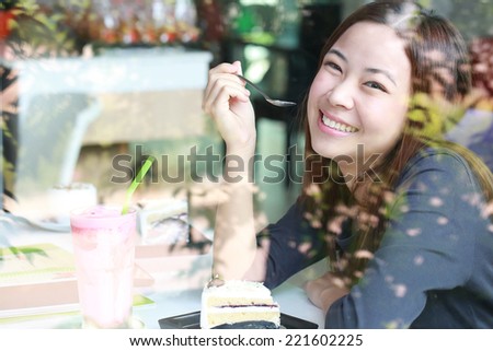 Young Asian women holding spoon for eat cake  beside mirror in cafe shop