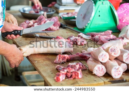 Butcher cut and slices pork leg in fresh market
