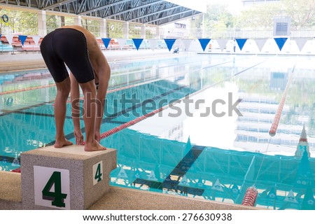 Swimmer on starting block for jump to swim and train.