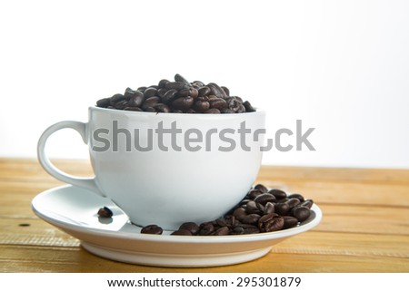 Coffee cup with beans on the wood board.