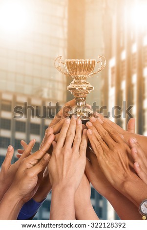 Success business with thier winner trophy holding by hands.