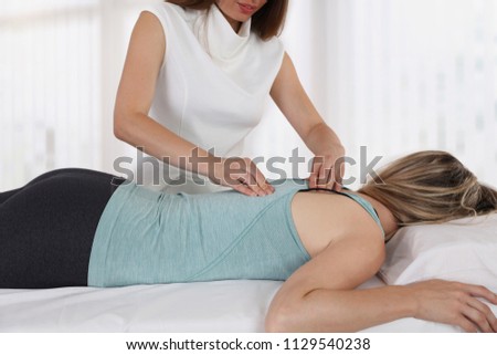 Woman having chiropractic back adjustment. Osteopathy, Physiotherapy, sport injury rehabilitation concept