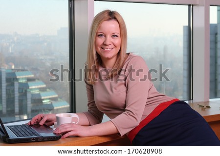 Pretty businesswoman with laptop near the window
