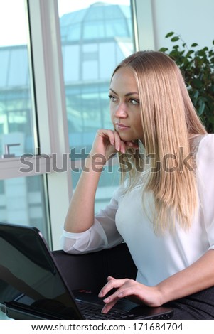 Young woman with laptop near the window in an office