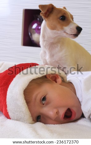 Cute little boy playing with his dog jack Russell terrier and wearing Santa hat