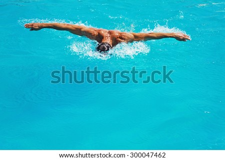 Strong athletic man swimming butterfly style in the pool