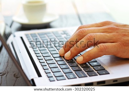 Close-up of male hands using laptop outside. Selective focus