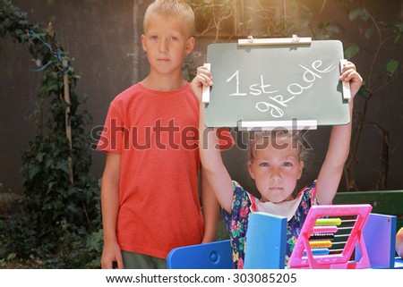 Boy and girl holding chalkboard with words first grade. Outdoor portrait