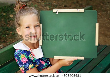 Little girl holding chalkboard. Outdoor photo