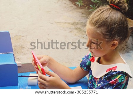 Stylish young girl counting on an abacus. Outdoor photo. Education and kids fashion concept