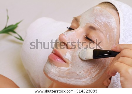 Young beautiful girl receiving clay facial mask in spa beauty salon.  Skin care, Beauty treatments.