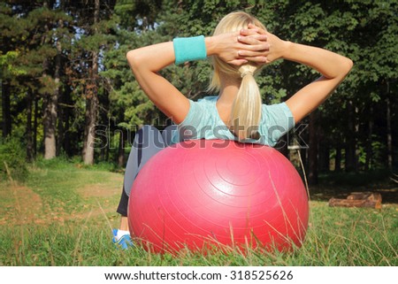 Young woman doing pilates outdoors in nature. Crunches on exercise pilates stability ball. Fitness, sport, workout, active lifestyle concept