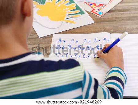 School Boy Writing on Paper writing the alphabet with Pencil . Kid, homework, education concept