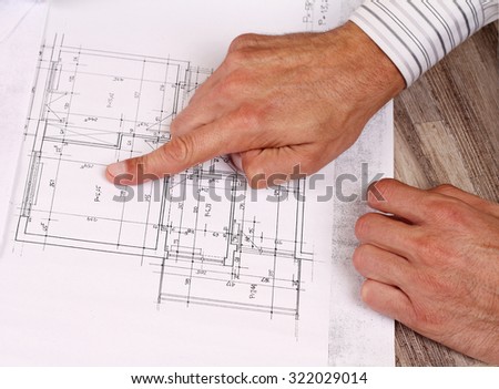 Architect showing project, house plans. Close up on male hand pointing at plan