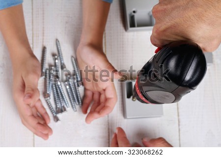 Father and son using electric screwdriver. Boy helping his dad with building work at home.  Family concept. DIY tools