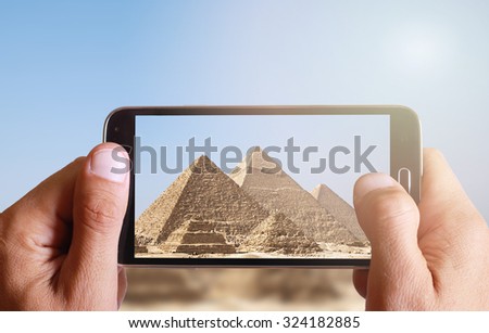 Male hand taking photo of Great pyramids in Giza with cell, mobile phone. Egypt holiday.