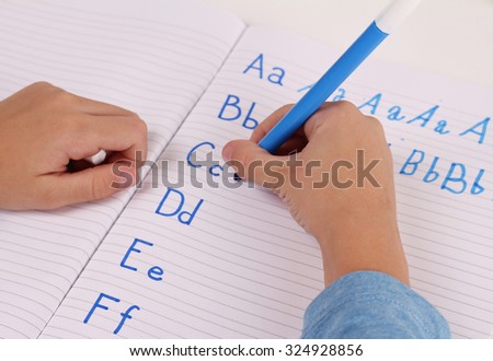 School Boy Writing on Paper writing the alphabet with Pencil . Kid, homework, education concept. Selective focus image