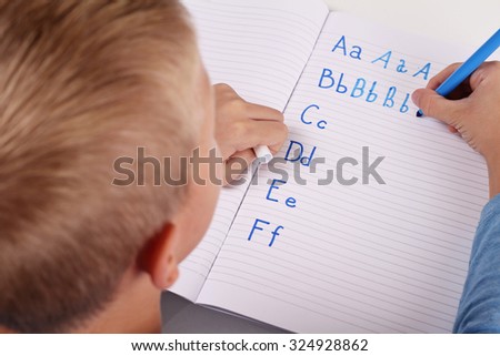 8 year old elementary school age boy writing the alphabet with Pencil . Kid, homework, education concept. Selective focus image