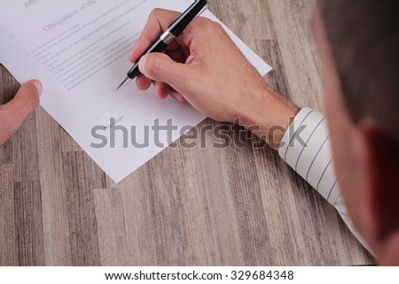 Close up Of Business Man Signing A Contract. Client signing credit agreement. Male hand signing papers. Lawyer, realtor.