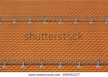 Tiled roof with snow guards - A roof covered with red tiles and snow guards attached.