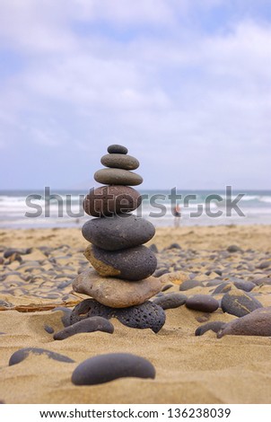 Balancing Stones - Balancing stone pebbles on beach with view of the Atlantic Ocean, North coast of Lanzarote near Famara, Canary Islands.