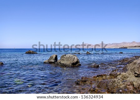 Coastal Landscape - Lanzarote coast line and blue Atlantic Ocean with mountains in the background, Canary Islands, Spain.