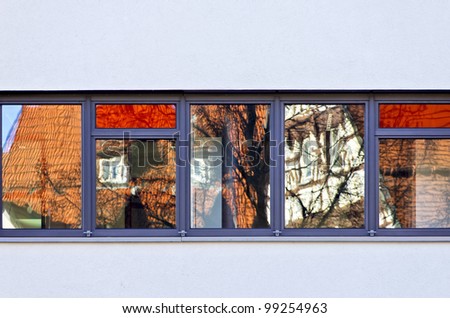 Modern versus old architecture - Reflections of old residential timber-framework houses in the windows of a modern architecture.