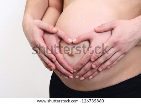 pregnant belly with hands om mom and dad in the form of a heart